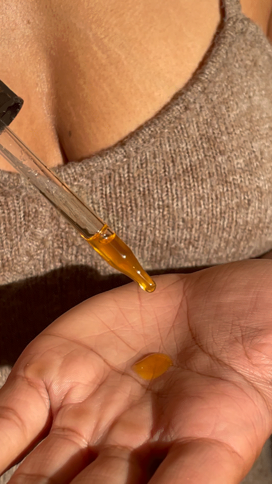 Gif of model female model using a dropper to put tiny drops of the oil on to the palm of her hand 