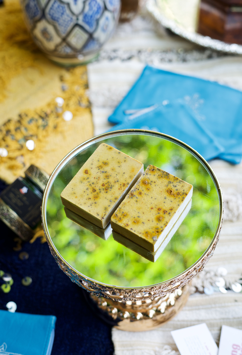 Two turmeric bar soaps are pictured on top a green soap dish 