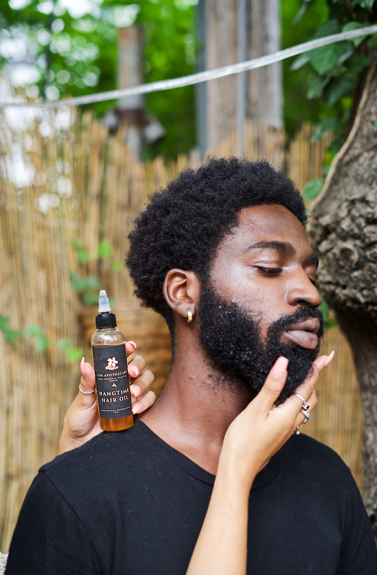 A male model with his full beard is shown with a female model holding the Hangtime Hair Oil in shot
