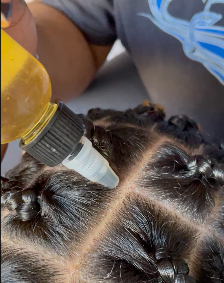 Close up shot of a female applying oil onto her scalp 
